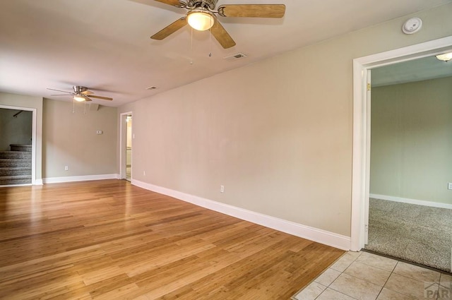 spare room featuring stairway, baseboards, visible vents, and ceiling fan