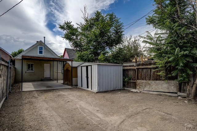 exterior space featuring a patio area, a storage shed, a fenced backyard, an outbuilding, and driveway