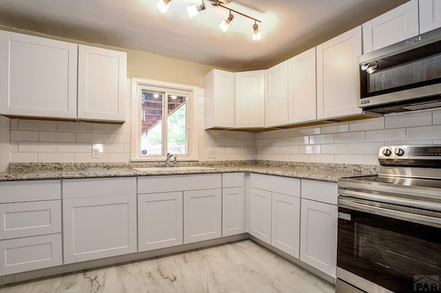 kitchen with a sink, decorative backsplash, stainless steel appliances, white cabinets, and marble finish floor