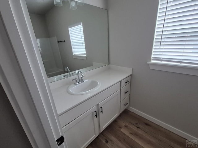 bathroom with a tub to relax in, baseboards, wood finished floors, and vanity