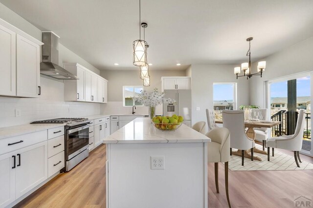 kitchen featuring stainless steel appliances, wall chimney exhaust hood, white cabinetry, and a center island