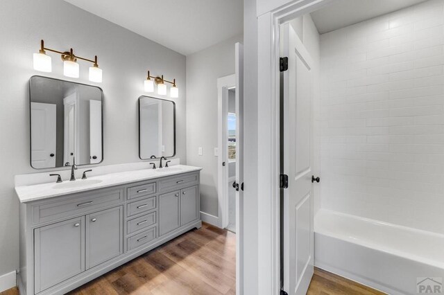 bathroom with double vanity, a sink, baseboards, and wood finished floors