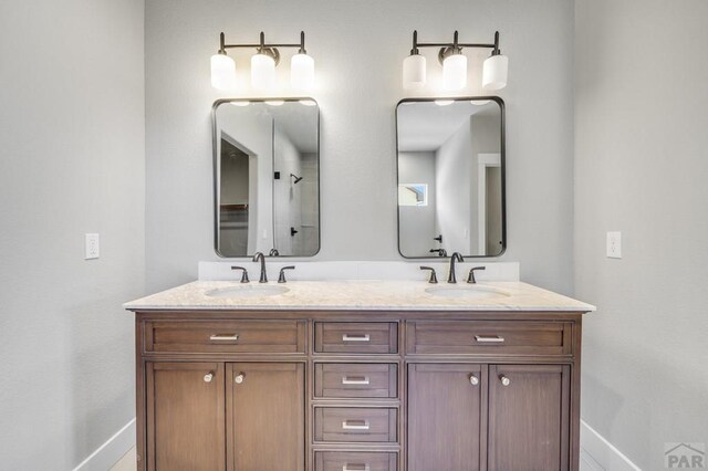 bathroom with double vanity, a sink, and baseboards