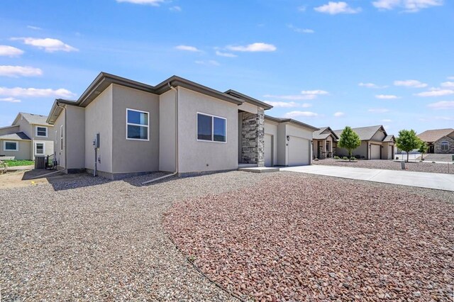 view of front of home with stucco siding, a garage, a residential view, stone siding, and driveway