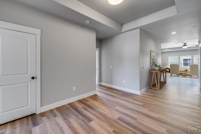 spare room with light wood-type flooring, ceiling fan, and baseboards