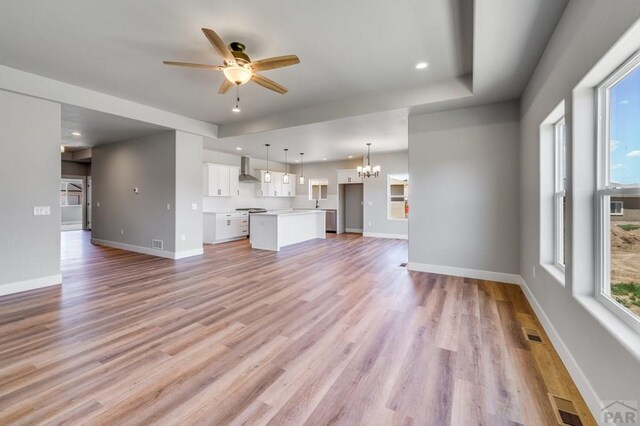 unfurnished living room featuring plenty of natural light, light wood-style flooring, visible vents, and baseboards