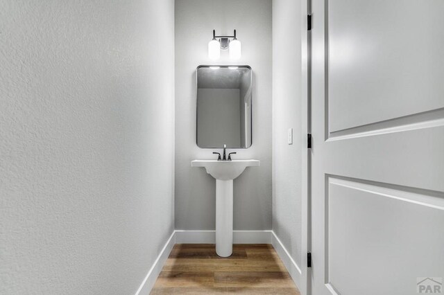 bathroom featuring baseboards, wood finished floors, and a textured wall