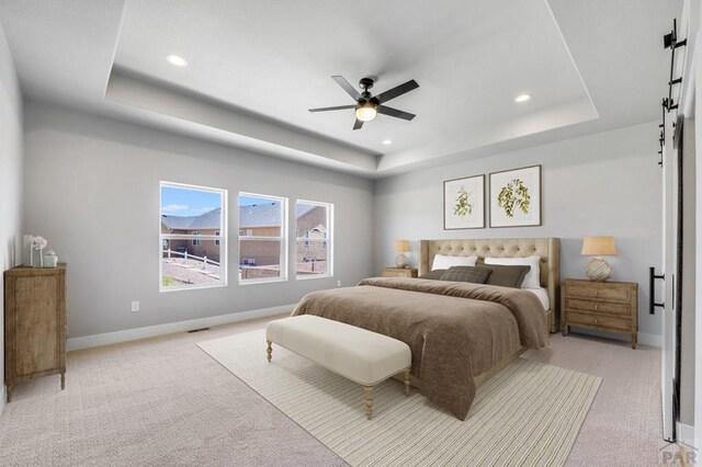 bedroom featuring a barn door, recessed lighting, light colored carpet, baseboards, and a raised ceiling