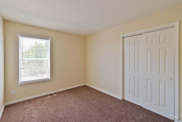 unfurnished bedroom with carpet floors, a closet, and baseboards