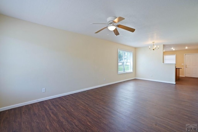 unfurnished room with dark wood-style floors, ceiling fan with notable chandelier, and baseboards