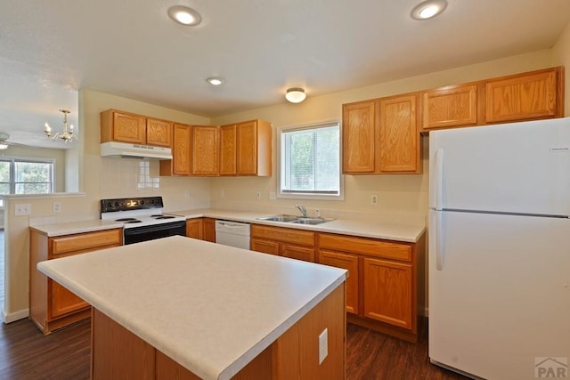 kitchen featuring white appliances, a kitchen island, light countertops, under cabinet range hood, and a sink