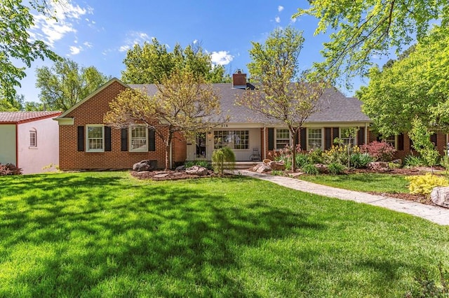 ranch-style house with a front yard, brick siding, and a chimney