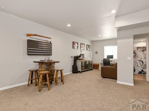 carpeted office space with a dry bar, baseboards, and recessed lighting