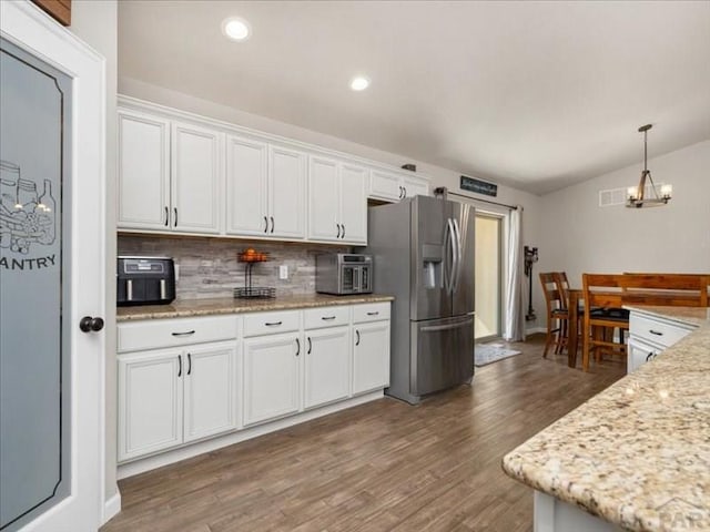 kitchen featuring stainless steel fridge, white cabinetry, vaulted ceiling, and wood finished floors