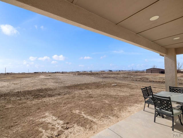 view of yard featuring a patio area, a rural view, and outdoor dining area