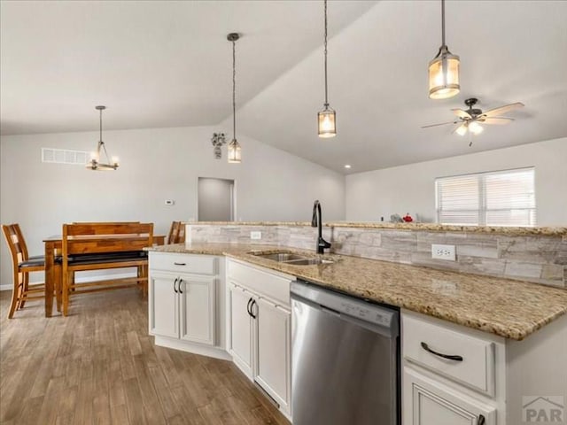 kitchen with lofted ceiling, wood finished floors, stainless steel dishwasher, white cabinetry, and a sink