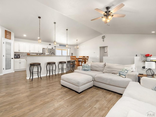 living room featuring a ceiling fan, lofted ceiling, light wood-style flooring, and recessed lighting