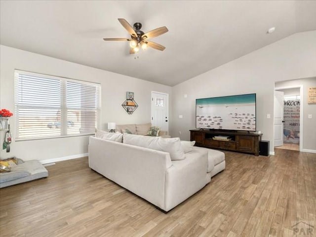 living room with lofted ceiling, light wood-type flooring, a ceiling fan, and baseboards