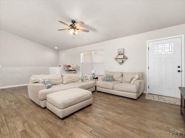 living area featuring a ceiling fan, baseboards, and wood finished floors