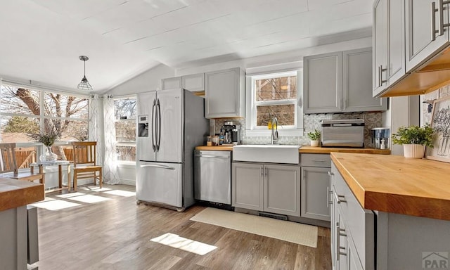 kitchen with a wealth of natural light, butcher block countertops, gray cabinets, a sink, and stainless steel appliances