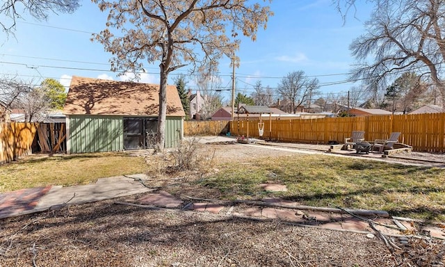 view of yard featuring a storage shed, an outbuilding, a fenced backyard, and a patio area