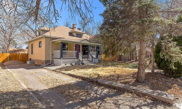 view of front of property with fence, roof with shingles, driveway, a porch, and a chimney