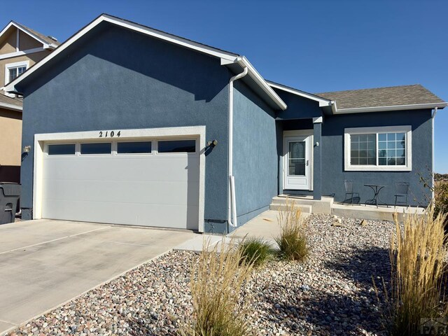 ranch-style home featuring an attached garage, driveway, and stucco siding