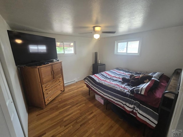 1622 Zuni Rd, Pueblo, CO 81001 - bedroom with wood finished floors, a baseboard heating unit, multiple windows, a textured ceiling, and ceiling fan