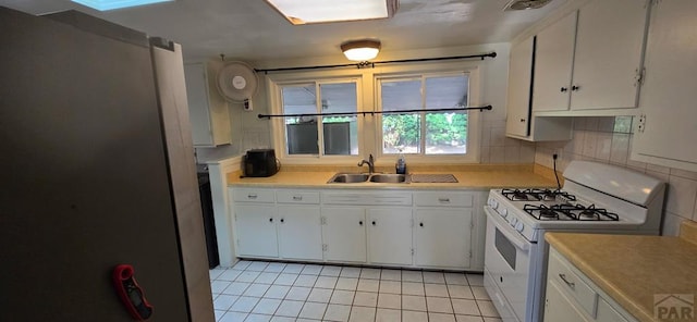 1622 Zuni Rd, Pueblo, CO 81001 - kitchen with white range with gas stovetop, light tile patterned floors, white cabinets, light countertops, and backsplash