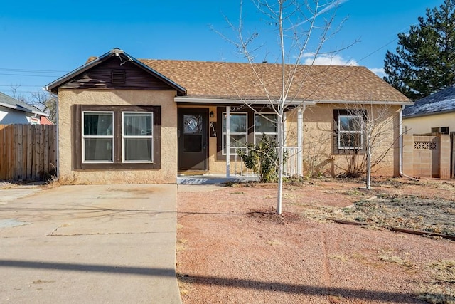 view of front of home with roof with shingles, fence, and stucco siding