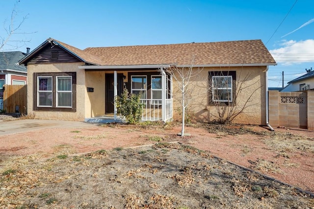 view of front of home featuring a shingled roof, fence, and stucco siding