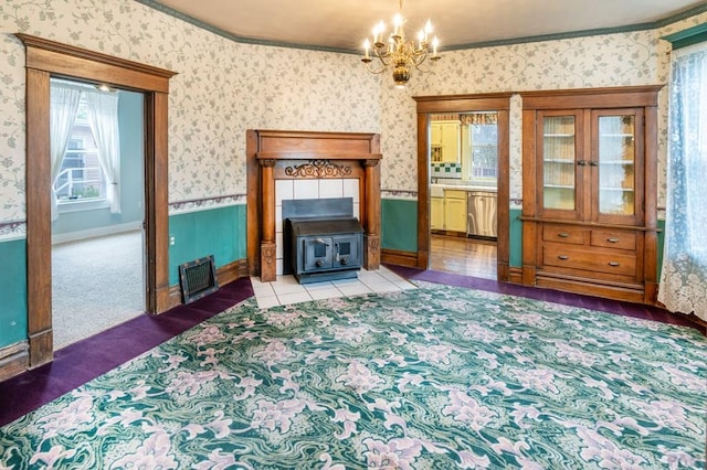living room featuring visible vents, carpet, a chandelier, wallpapered walls, and a wood stove