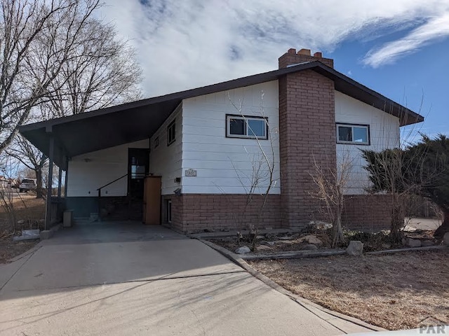 view of side of home featuring an attached carport, driveway, and a chimney