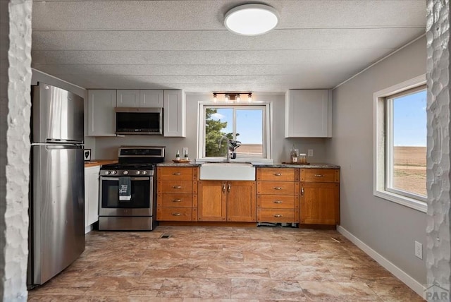 37155 E Jones Rd, Yoder, CO 80864 - kitchen with a sink, a wealth of natural light, brown cabinets, and appliances with stainless steel finishes