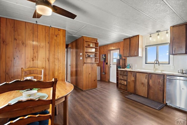 37155 E Jones Rd, Yoder, CO 80864 - kitchen with dark wood finished floors, stainless steel dishwasher, a ceiling fan, and wood walls