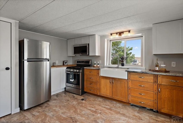 37155 E Jones Rd, Yoder, CO 80864 - kitchen featuring white cabinetry, a sink, brown cabinets, and appliances with stainless steel finishes