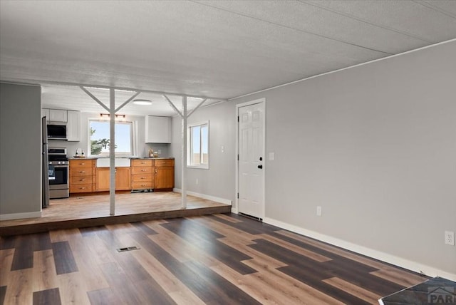 37155 E Jones Rd, Yoder, CO 80864 - interior space featuring baseboards, white cabinetry, wood finished floors, and stainless steel appliances