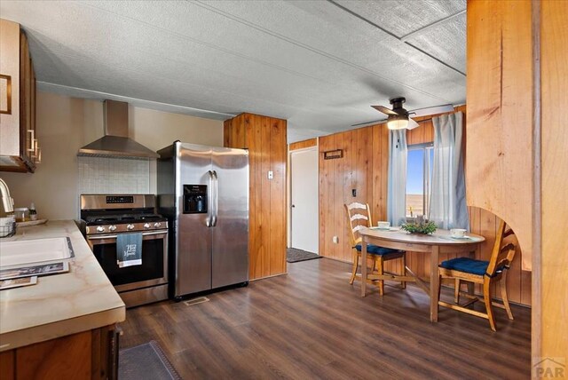 37155 E Jones Rd, Yoder, CO 80864 - kitchen featuring dark wood-style floors, stainless steel appliances, light countertops, wall chimney range hood, and a sink