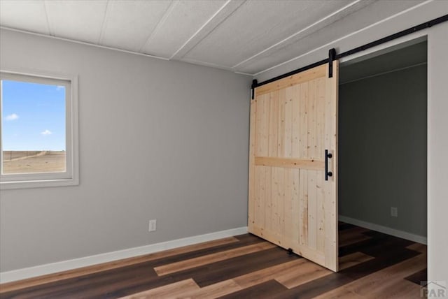 37155 E Jones Rd, Yoder, CO 80864 - unfurnished bedroom featuring baseboards, wood finished floors, and a barn door