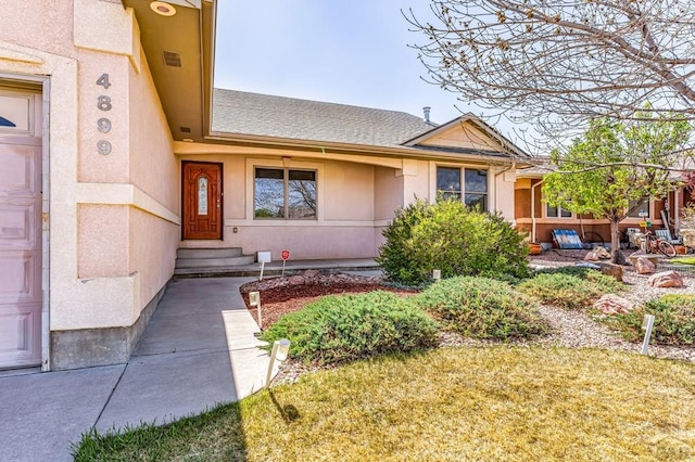 doorway to property featuring stucco siding