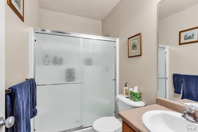 bathroom featuring a textured wall, vanity, a shower stall, and toilet