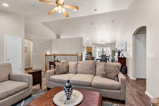living area with arched walkways, baseboards, visible vents, ceiling fan with notable chandelier, and wood finished floors