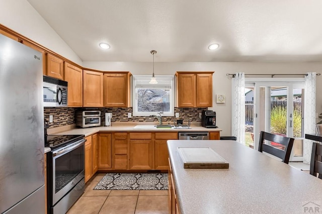 kitchen with backsplash, light countertops, stainless steel appliances, and a sink