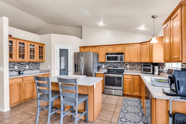 kitchen with a kitchen breakfast bar, tasteful backsplash, vaulted ceiling, a kitchen island, and appliances with stainless steel finishes