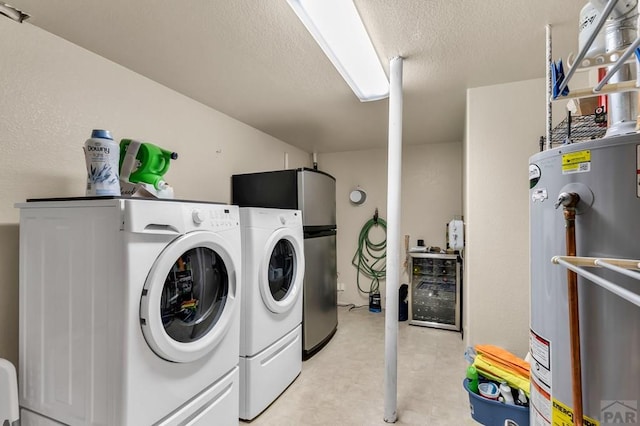laundry area featuring washing machine and clothes dryer, a textured ceiling, gas water heater, light floors, and laundry area
