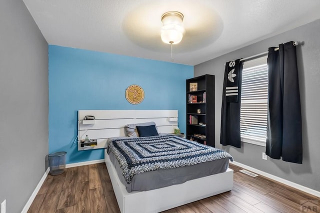 bedroom featuring wood finished floors, visible vents, and baseboards