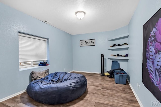 sitting room with wood finished floors, visible vents, and baseboards