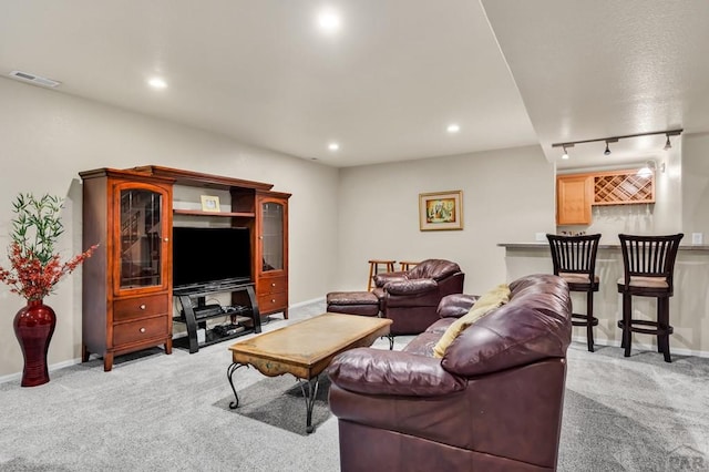 living area with rail lighting, light carpet, visible vents, and baseboards