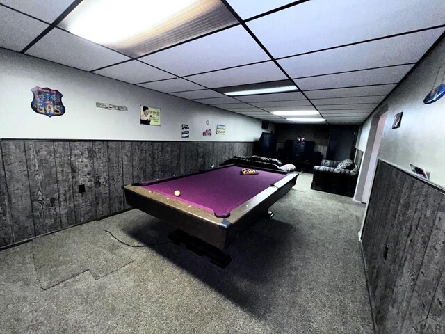 game room featuring carpet, wainscoting, wooden walls, and a drop ceiling