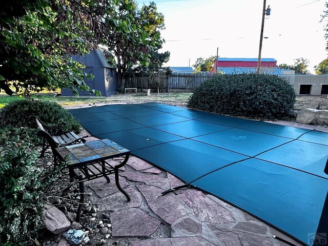 view of pool with an outbuilding, a patio area, fence, and a fenced in pool